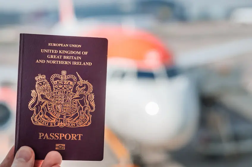 Red British passport with plane in background