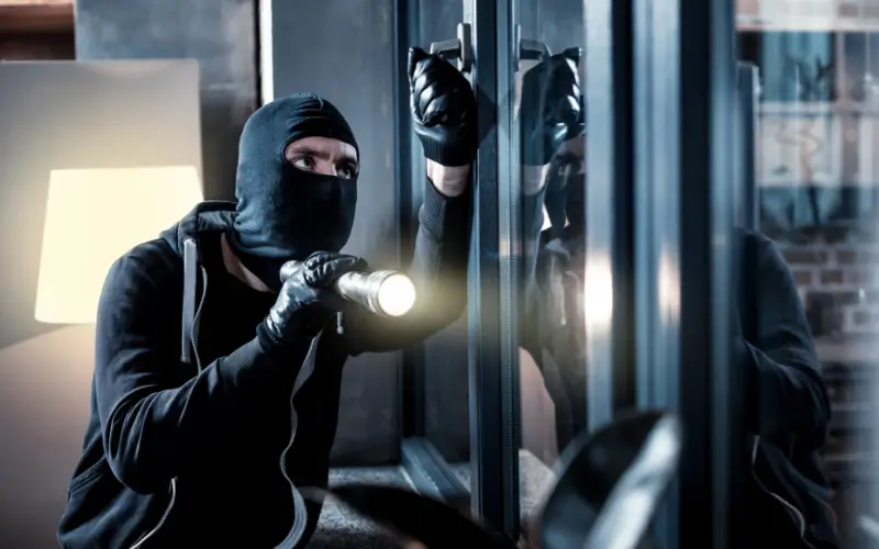 Burglar wearing a balaclava at night trying to break into a home