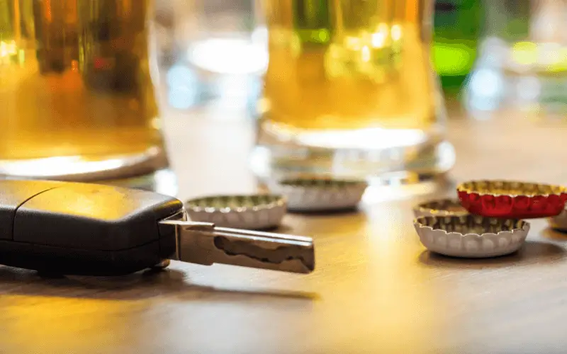 Car key on table with drink and bottle tops