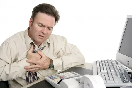 Man clutching chest in office, possibly suffering from indigestion or heartburn