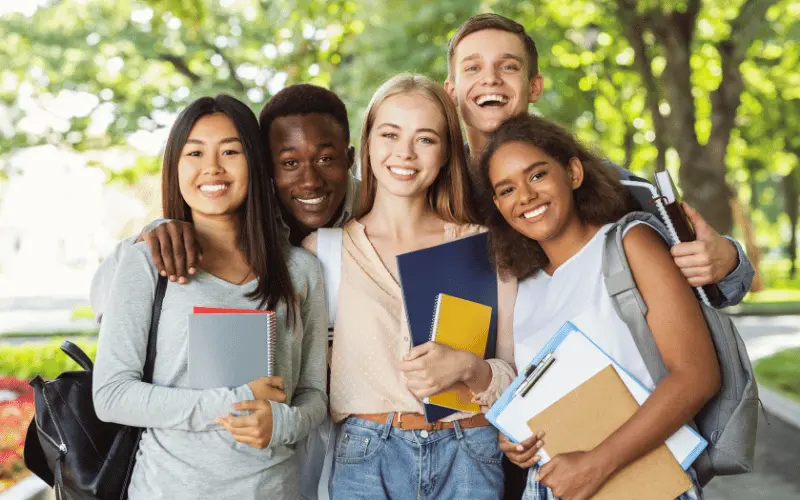 Happy international university students on campus holding notebooks