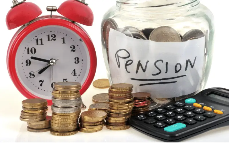 Pension pot with coins in, a red alarm clock, calculator and coins