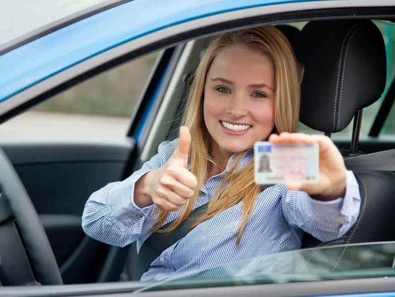 Woman showing driving licence with thumbs up