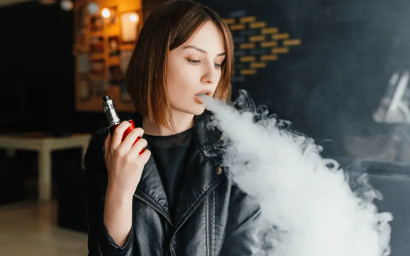 woman blowing smoke from vape